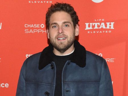 Jonah Hill in a black jacket poses for a picture at an event.